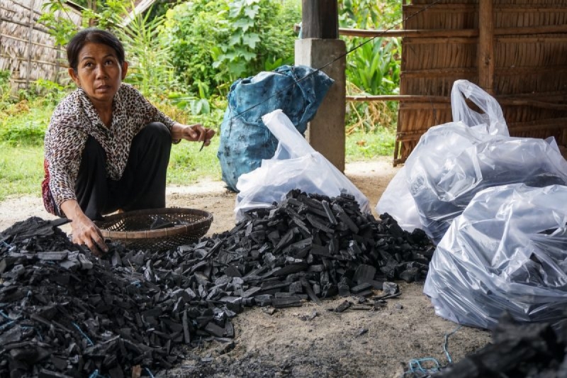 Samith Neath puts pieces of charcoal into bags beneath her house in Takeo province’s Traing district last month. (Sonia Kohlbacher/The Cambodia Daily)