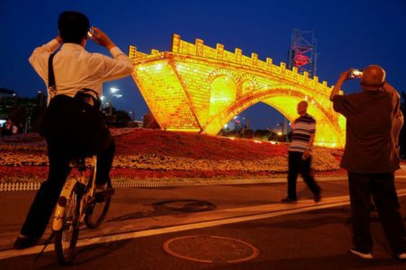 People take pictures of the "Golden Bridge on Silk Road" installation by artist Shu Yong, set up ahead of the Belt and Road Forum in Beijing, China May 10, 2017. REUTERS/Thomas Peter